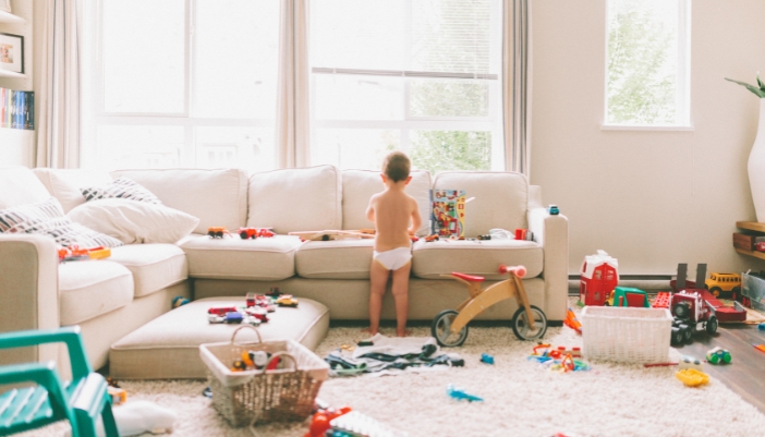 A toddler playing with big blocks all over a childproofed living room 