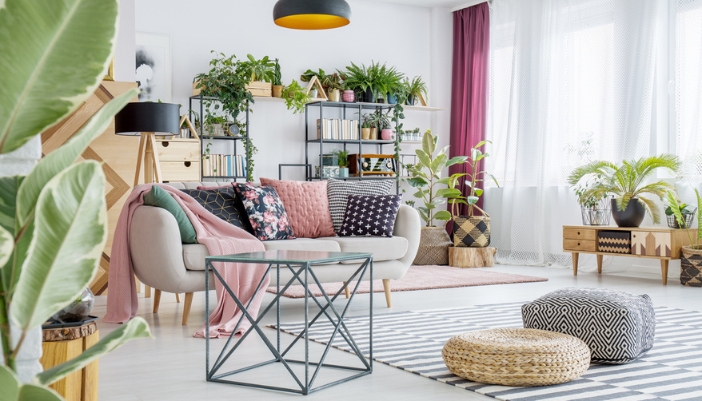 A well-lit, colorful living room filled with plants, flowers, and natural tones.