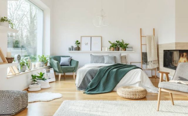 front view of a modern boho bedroom with lots of plants, a bed in the middle, and an accent chair on both sides