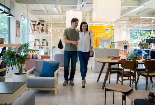 front view of a man and a woman walking through a furniture store and smiling