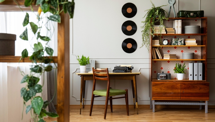A home office with a bookcase with books, plants, and display items.