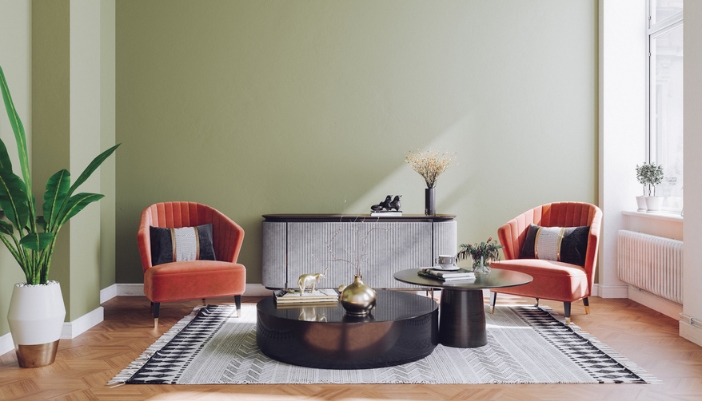 Two pink armchairs sit in front of a green wall and with black accent pieces.