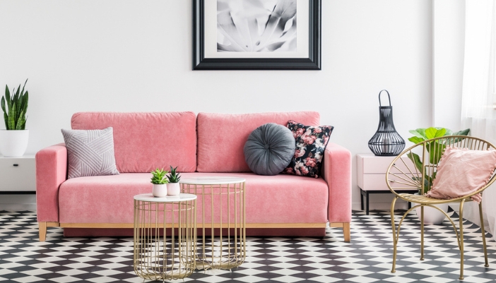 A pastel pink couch with gold and black accents surrounding it.