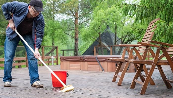 Man cleaning outdoor patio, scrubbing the floor