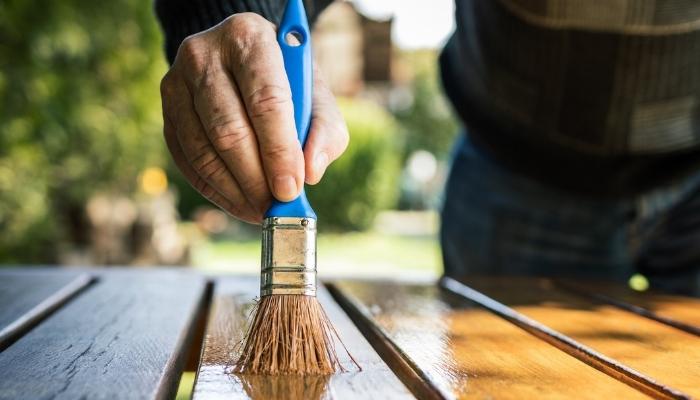 Man adding coat of sealant to wood furniture
