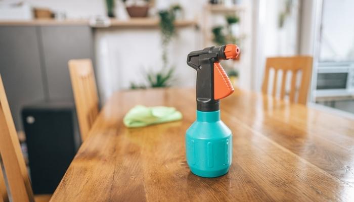 Spray bottle and rag on wooden table at home