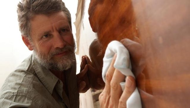 man polishing wood furniture piece