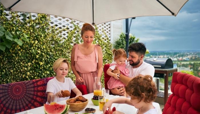 family eating on patio under umbrella