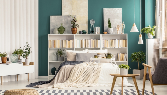 Stylishly arranged bedroom with bed, bookcase, tables, and a chair