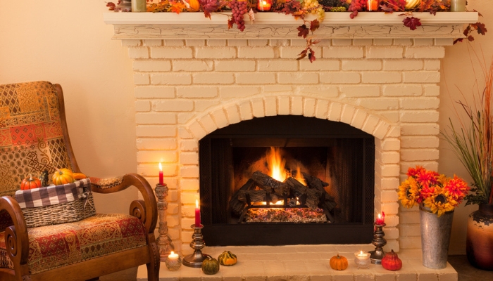 A fireplace burns with fall decor surrounding it.