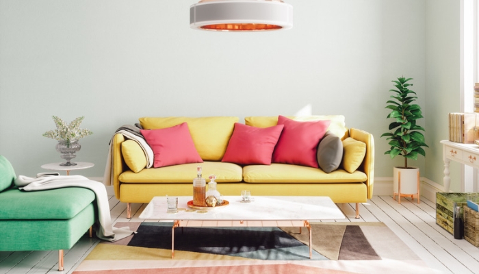 A yellow couch with pink pillows and a green armchair sit in a neutral living room