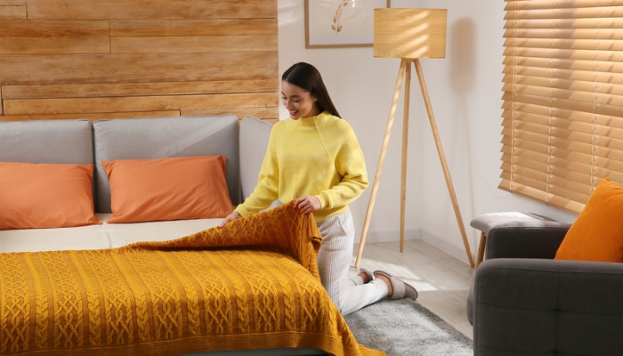 A woman puts golden covers on a converted sofa couch