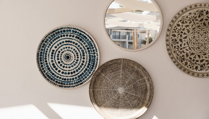 Three boho baskets placed on a wall with a circle mirror as a gallery wall
