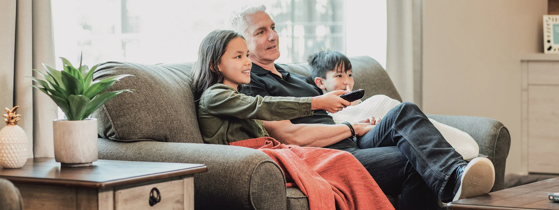 A family gathers together to watch television on a Flexsteel sofa