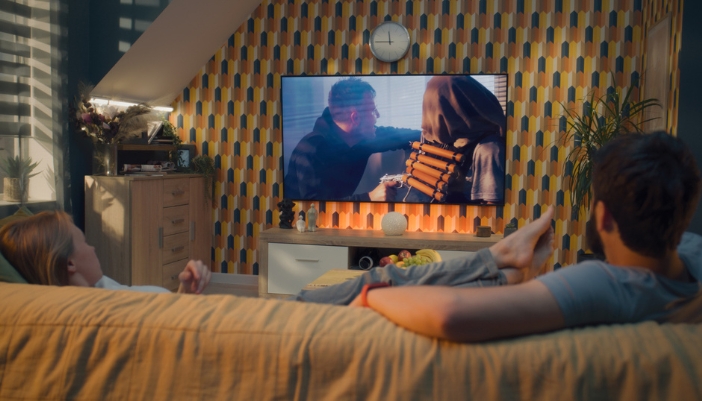 A couple watching TV while staying super comfy on the couch