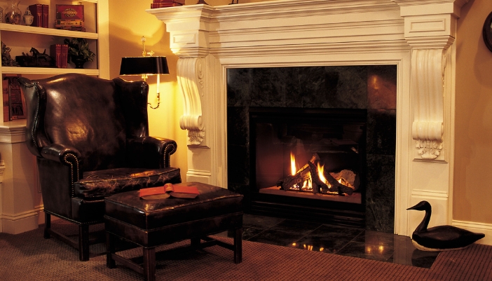 A dark leather armchair and ottoman in front of an active fireplace