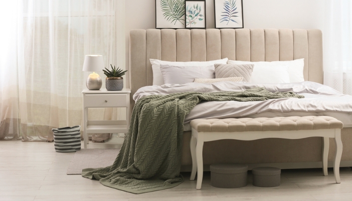 A neutrally upholstered white bench sits at the end of the bed.