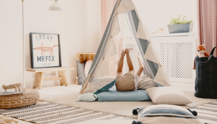 A boy plays in his neutrally colored playroom in a play tent.