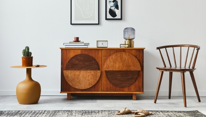 A vintage cabinet sits between a metal table and a wooden chair.