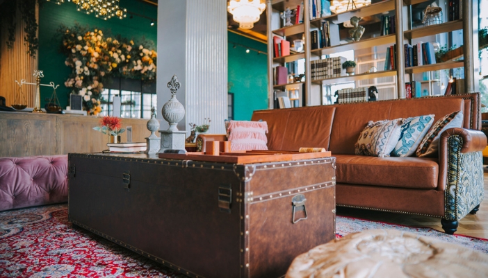 A vintage leather couch sits behind an old suitcase coffee table.