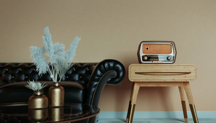 A retro inspired black leather couch sits beside a vintage side table and radio.
