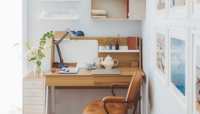 A small desk with shelves and cabinets above it in a well-lit room.