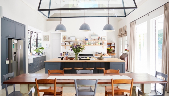 A dining room/kitchen combo with an elaborate pendant light above the table.