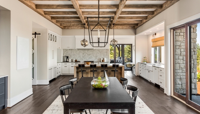 A dining room/kitchen combo with dark wood and a metal pendant light above the table.