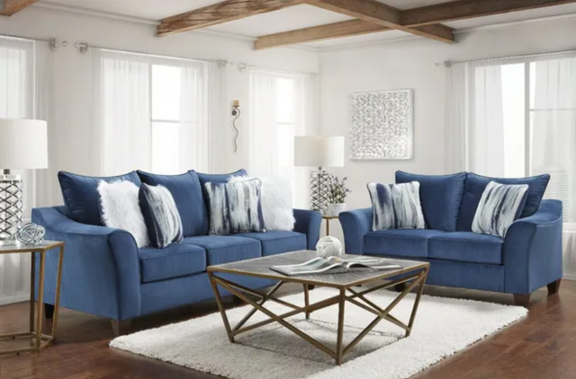 front view of a formal living room with a blue fabric sofa and loveseat around a glass coffee table and white rug