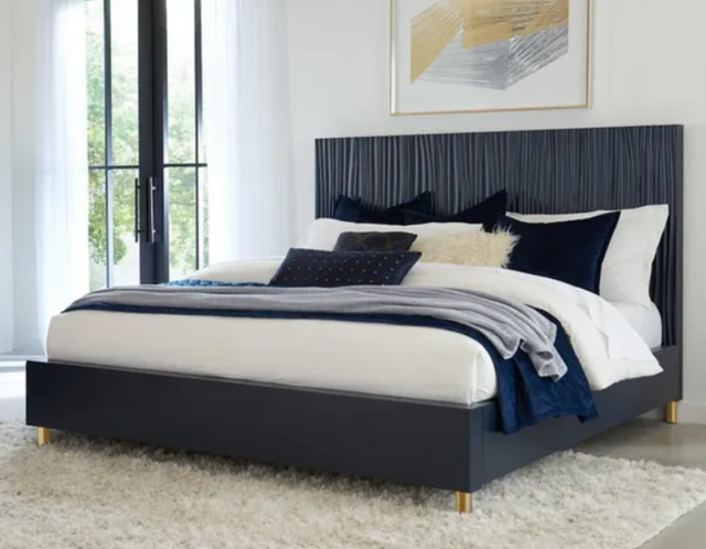 front view of a blue modus panel king bed frame in a contemporary bedroom with white walls and large windows