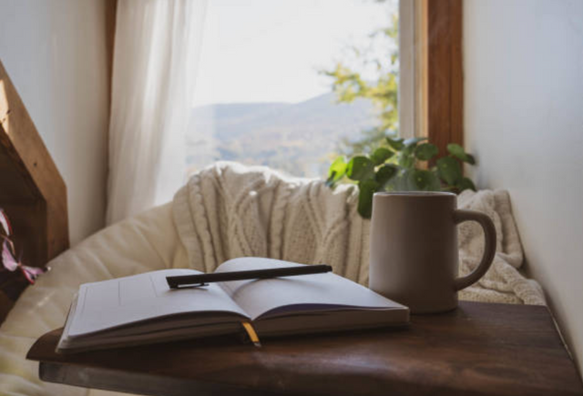 front view of a small reading nook with a large chair, blankets, a book, and a mug