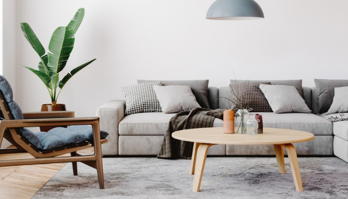 A natural wood oval coffee table in front of a large gray sofa.