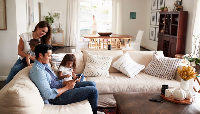 A family gathers together on a neutral colored sectional at home.