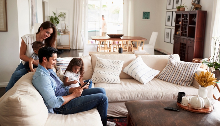 A family gathers together on a neutral-colored sectional at home.