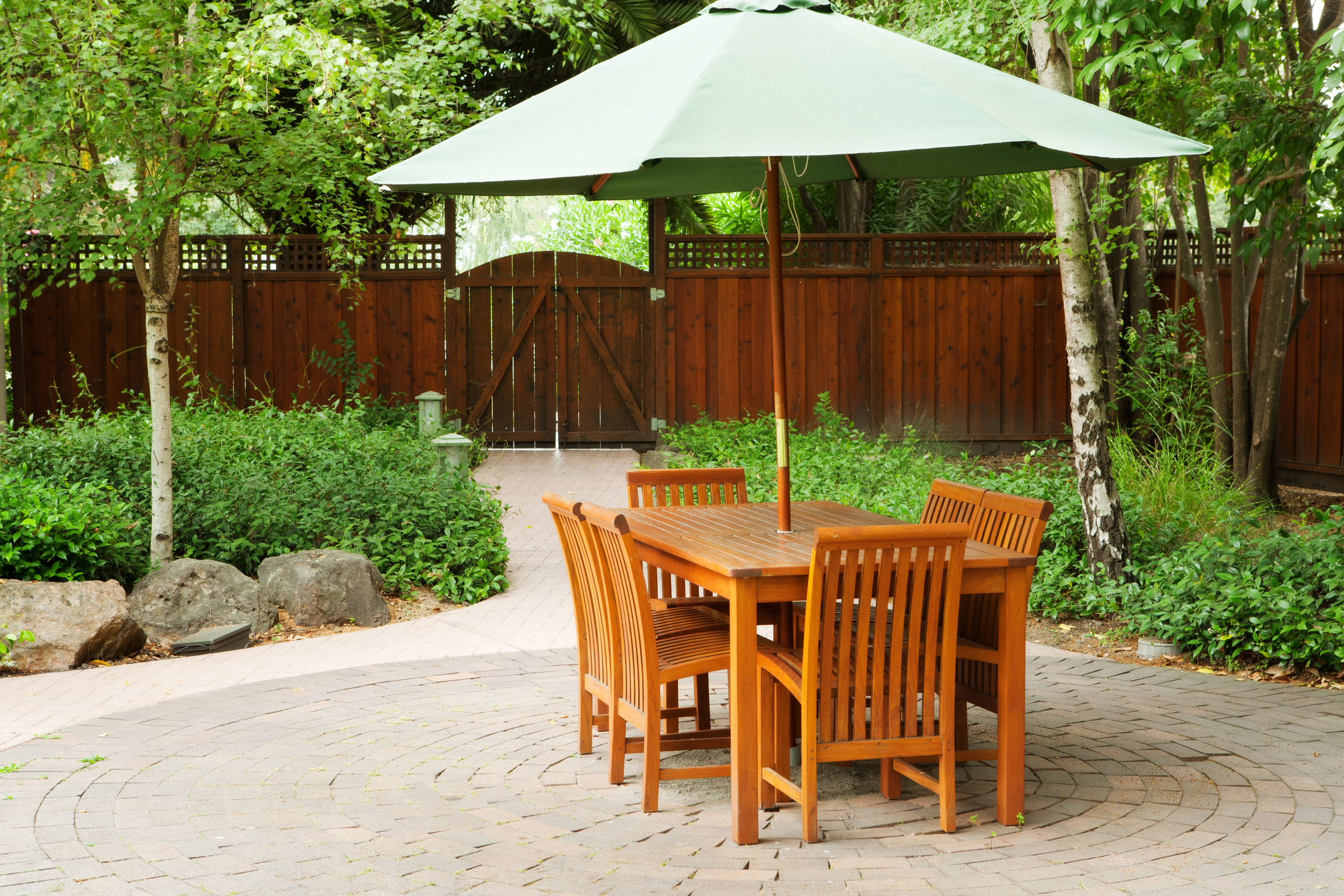 garden patio dining set with green umbrella on sunny afternoon