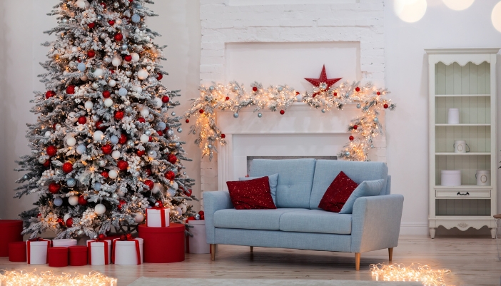 A holiday themed living room with a loveseat next to the tree and presents