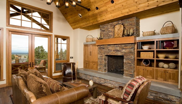 A large rustic living room with a huge fireplace, rustic coffee table, candles in tapers, and leather-toned seating