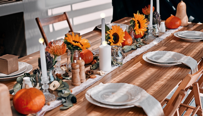 A wooden dining table is decorated with pumpkins and sunflowers with a rustic vibe.