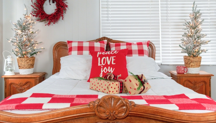 Holiday throw pillows and decor decorate a guest bedroom with wooden furniture.