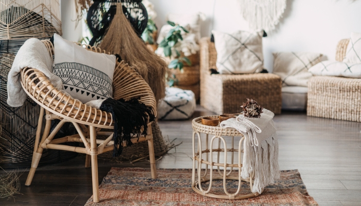 A wicker chair with bohemian elements sits in a brightly lit living room.