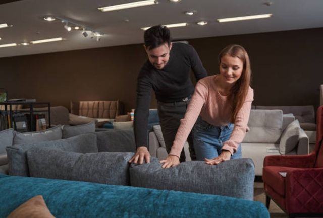 front view of a man and a woman touching a couch in a furniture store and smiling