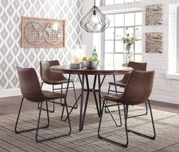 round wooden dining table with thin metal pedestal base and matching chairs in a small modern dining room