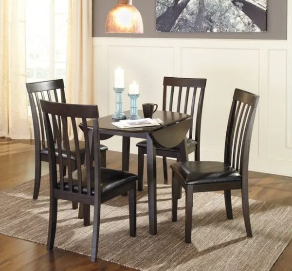 round wood dining table with foldover sides and matching wooden chairs in a small modern dining space