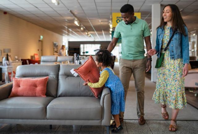 Front view of a family of three walking through a furniture store