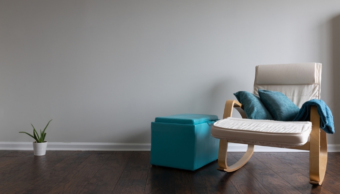 A rocking chair next to a bright turquoise storage ottoman with a lift lid