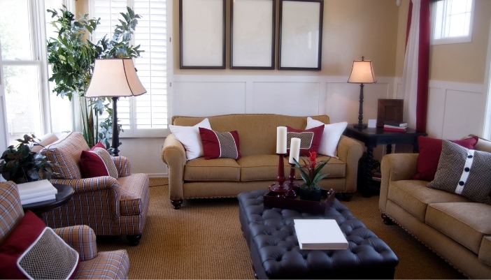 A stylish living room with two dark ottomans in the center, one holding a tray with home decor