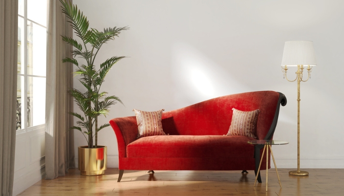 A velvet red daybed sits in a modern living room with a neutral wall. 