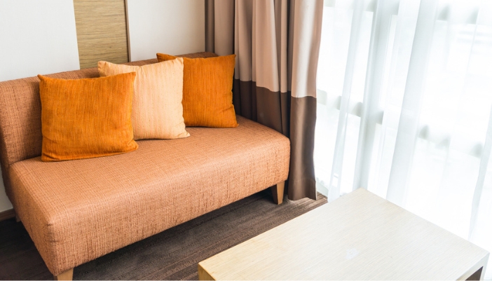 A orange daybed with throw pillow son top.