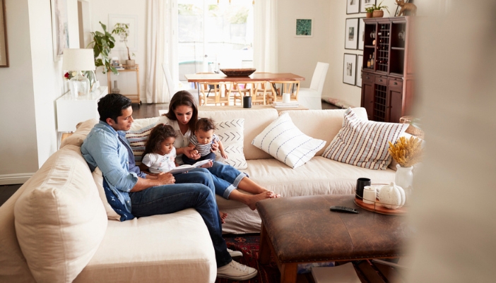 A family sits in the corner of their sectional in a home and reads together.