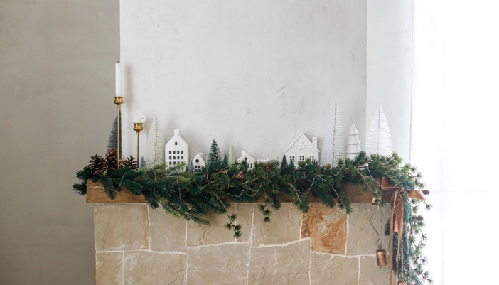 A mantel with holiday greens and white accent decor.